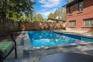 Water reflection in shady backyard Inground Rectangle Pool 14x28 with Interlock pool surround and Terrazzo Caribbean Liner by Latham Pools