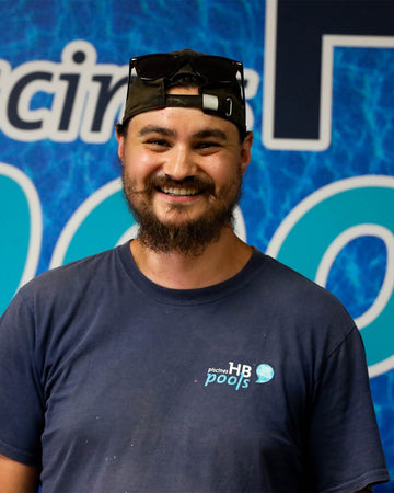 Pool chemistry technician wearing a dark blue t-shirt with an HB Pools logo in front.