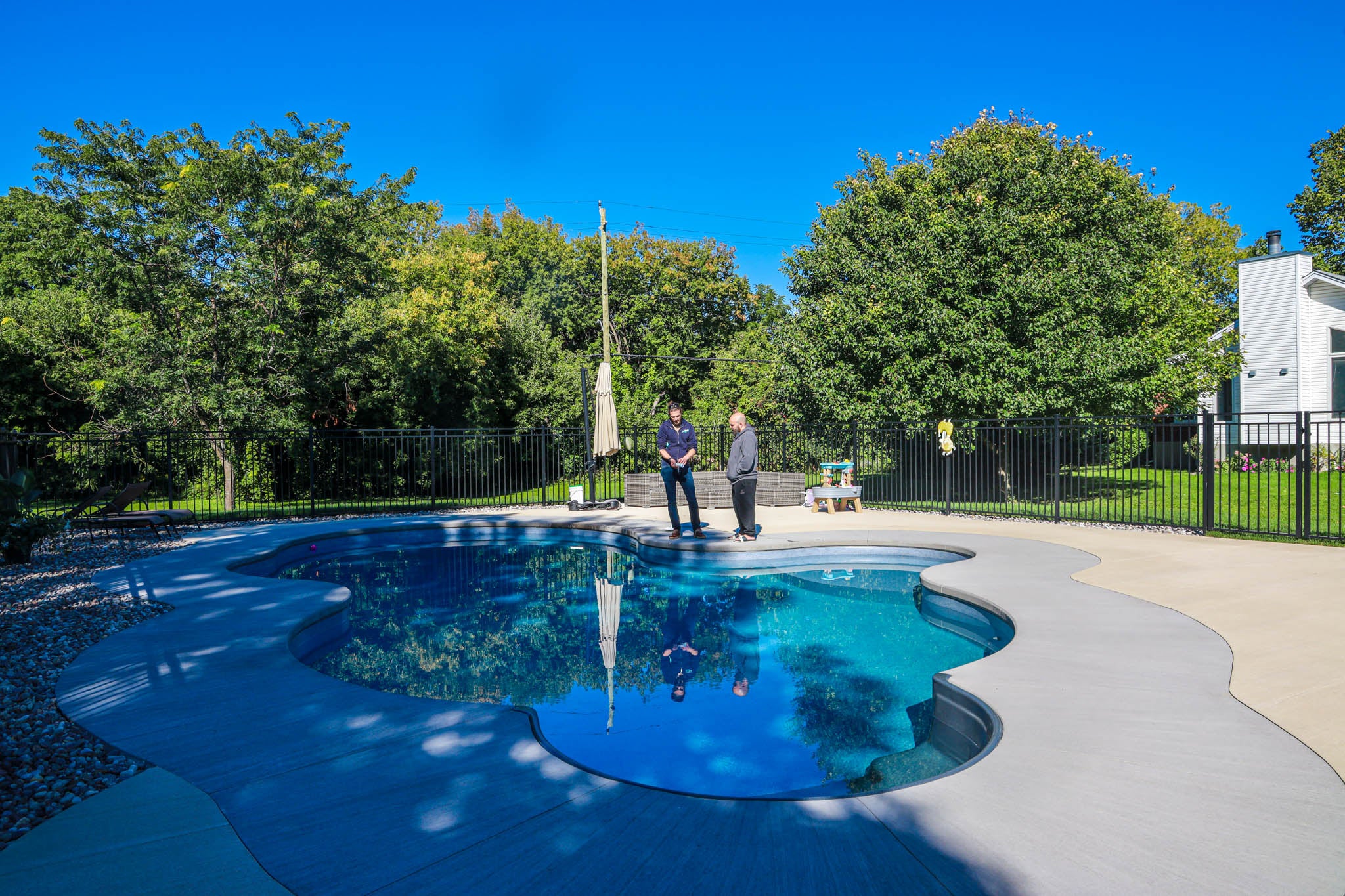 HB Pools service technicians explaining pool chemistry next to a newly built Inground Swimming pool.