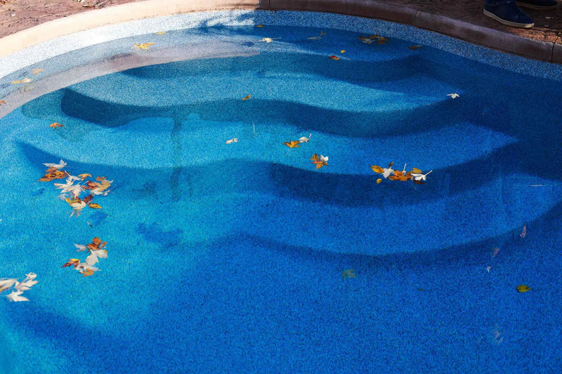 Close-up of blue textured pool liner on internal stairs with autumn leaves floating in the water | HB Pools