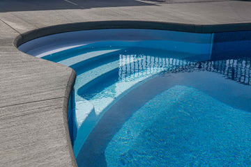 Close-up of vinyl inground pool steps with textured concrete decking installed by HB Pools in Navan, Ontario, highlighting smooth pool entry and durable materials.
