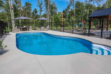 Custom vinyl inground swimming pool with curved steps and spacious concrete deck, installed by HB Pools in Navan, Ontario, featuring outdoor seating and a fenced backyard.