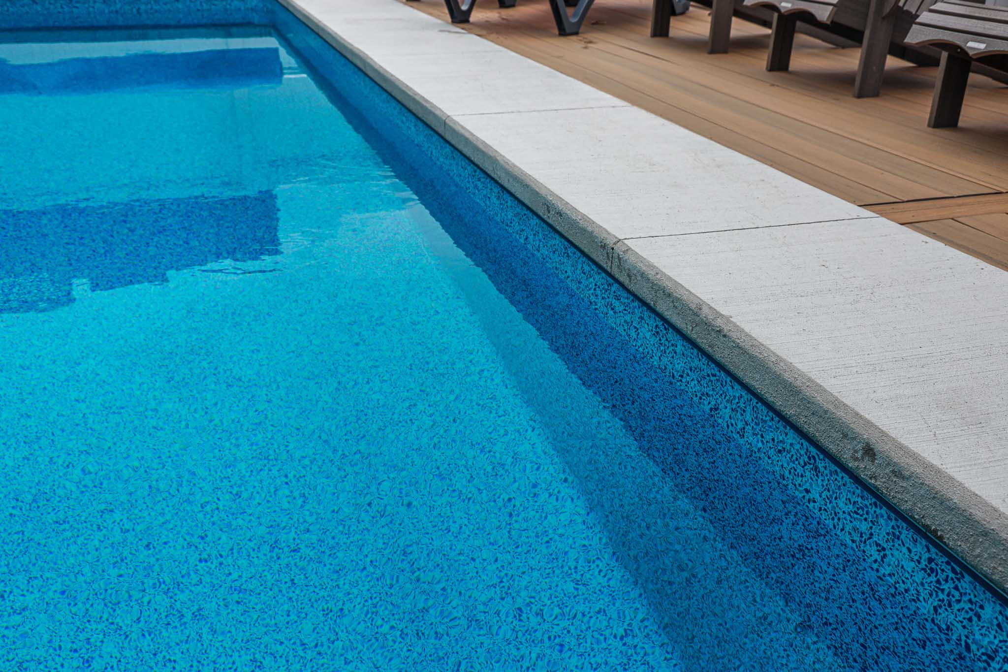 Close-up of clean concrete bullnose pool coping and stardust blue vinyl liner with detailed pattern, installed by HB Pools in Rockland, Ontario, highlighting precise craftsmanship.