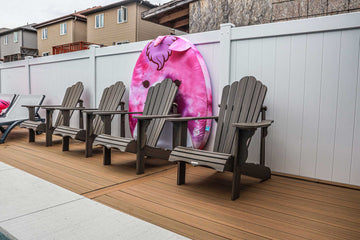 Row of Adirondack chairs on wood composite decking next to a vinyl inground pool, featuring a colorful unicorn float, installed by HB Pools in Rockland, Ontario.