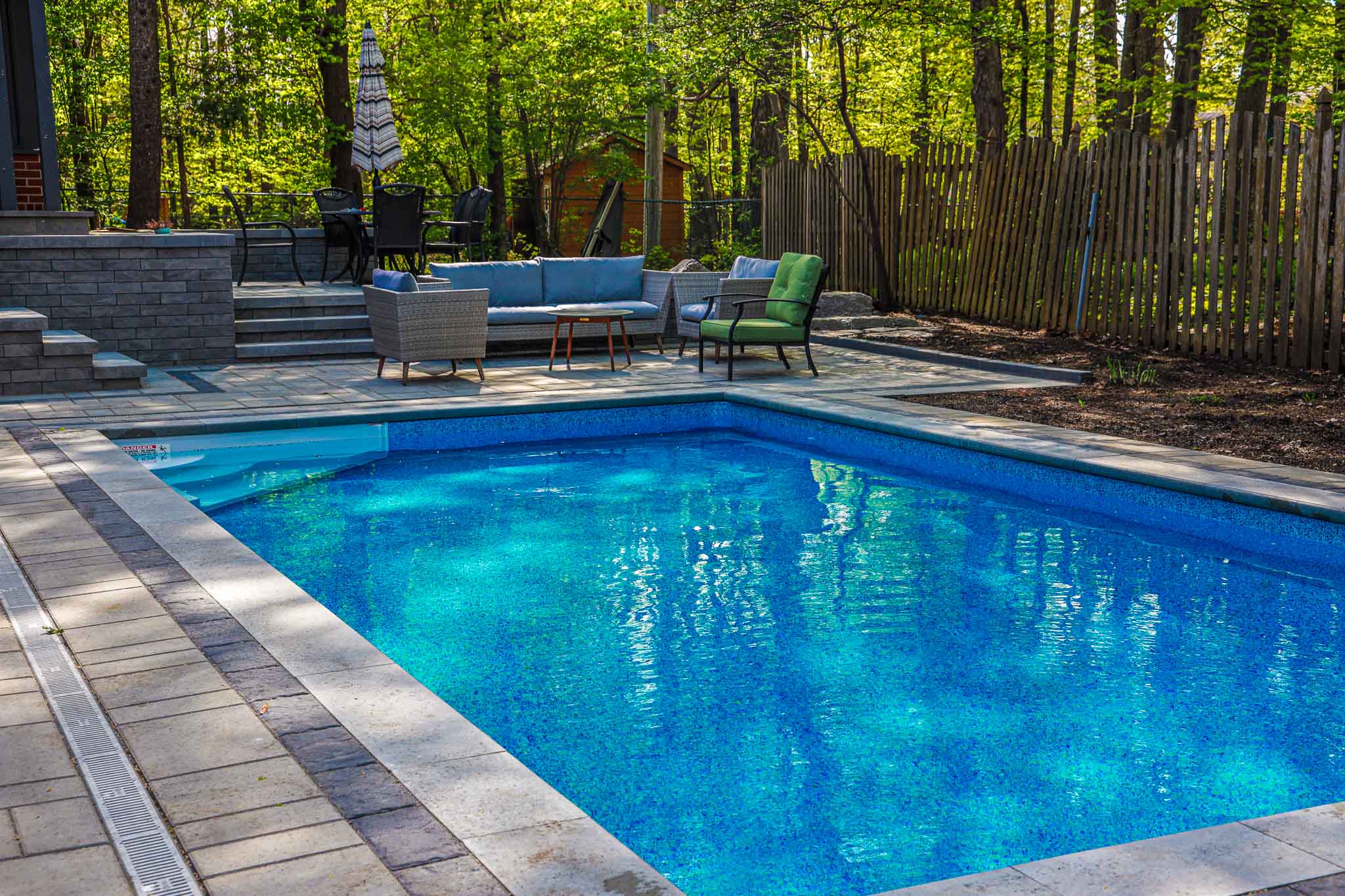 Inground Rectangle Pool 14x28 with Interlock pool surround and cozy seating and dining areas.