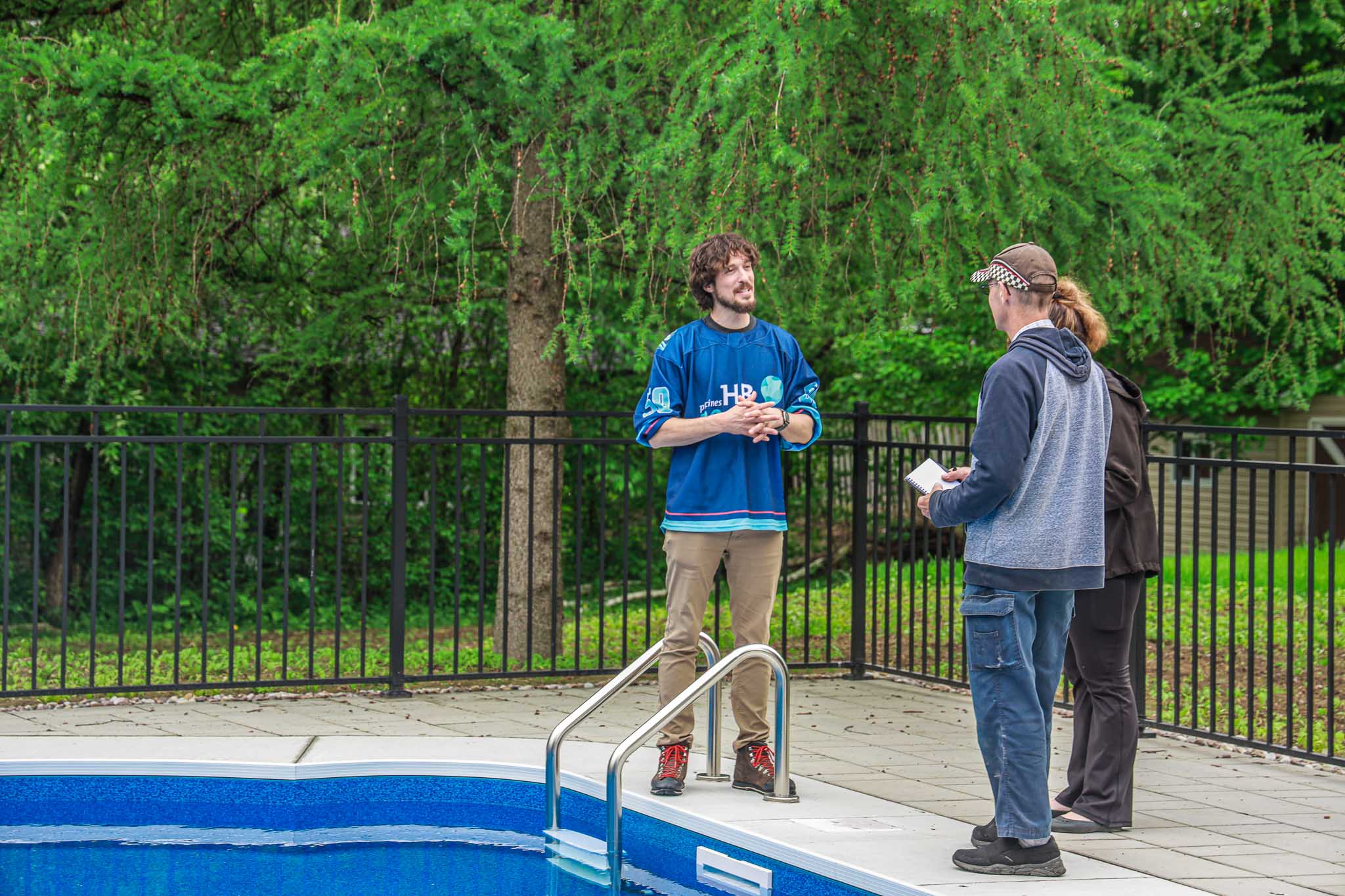 HB Pools technician consulting with clients beside a vinyl inground pool in Limoges Ontario, demonstrating expert customer service and pool maintenance advice from a trusted local pool builder.