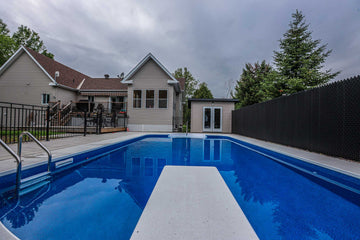 Vinyl inground swimming pool with diving board installed by HB Pools in Limoges, Ontario, featuring a spacious backyard, modern pool design, and privacy fencing.