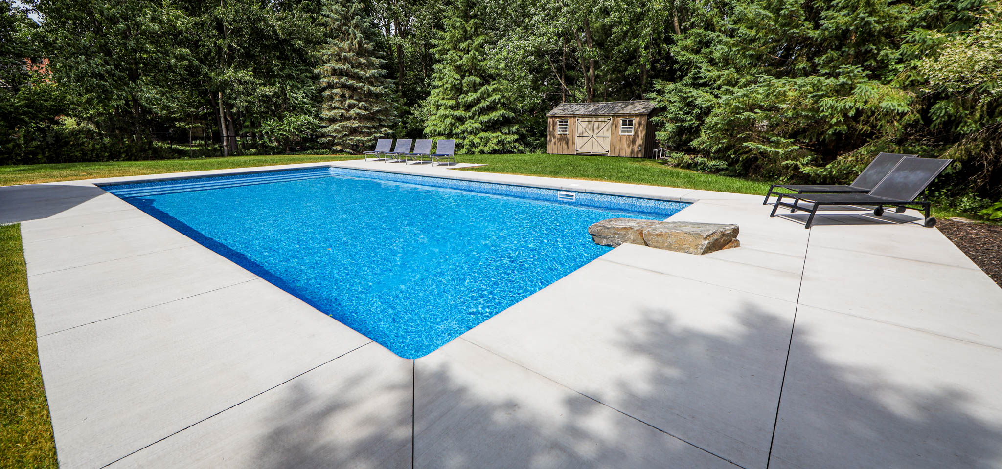 Inground Pool in Ottawa Manotick with a diving rock & lounger chairs
