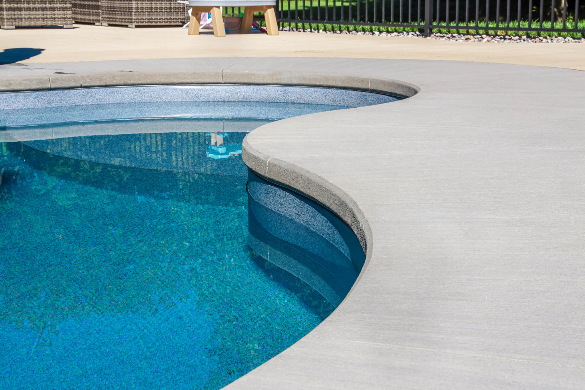Freeform brushed concrete with bullnose finish on a new pool installation project in Ottawa