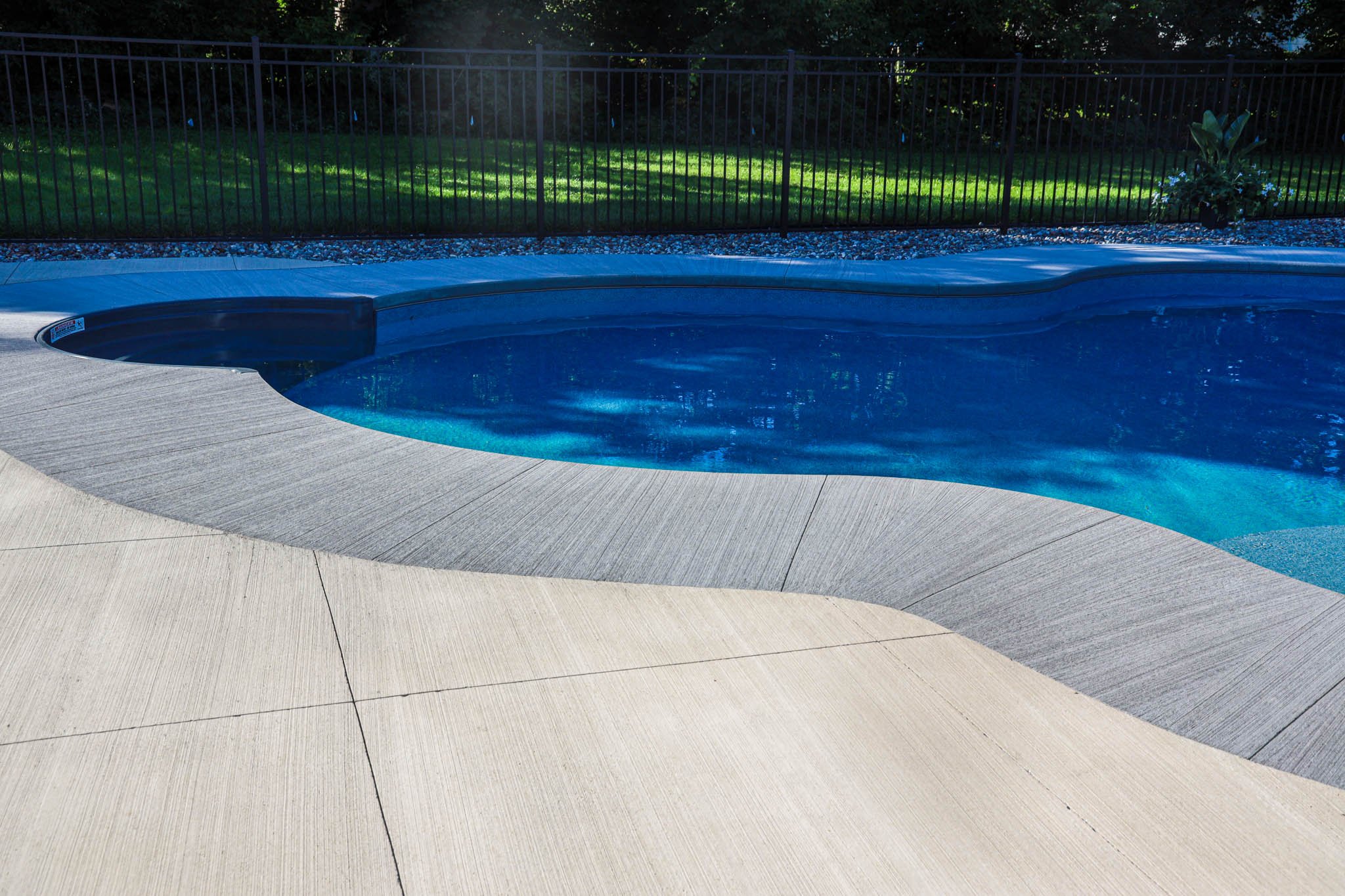 2 tone grey brushed concrete pool surround for a new pool construction in Nepean with a grey curved step 