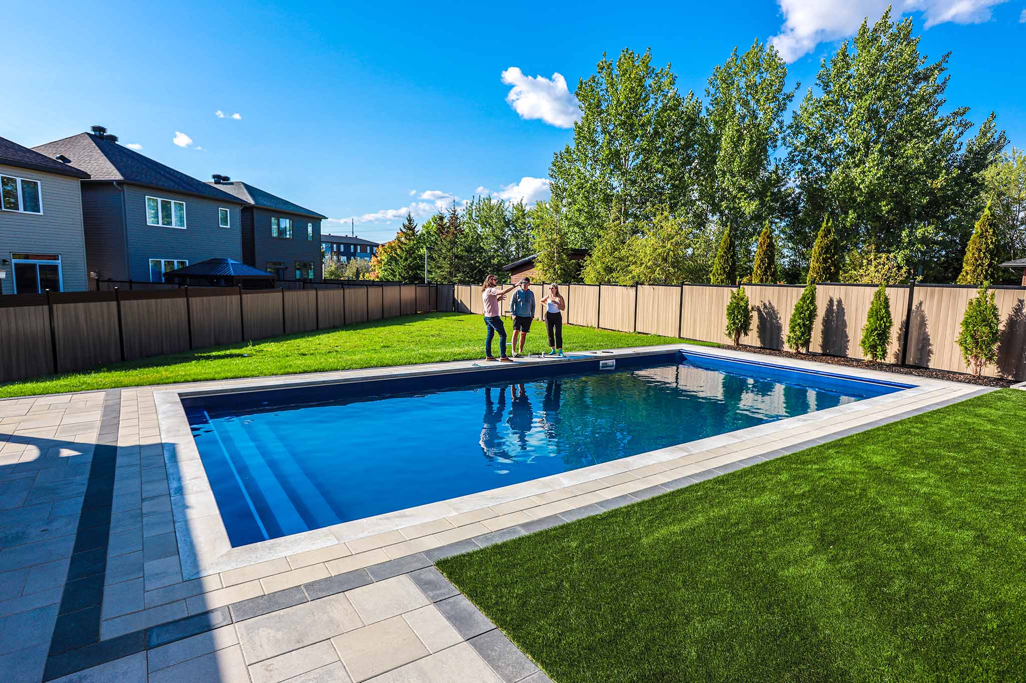 Pool technician explaining pool maintenance for a Newly installed inground pool by HB Pools, featuring a modern design with a spacious patio and lush landscaping