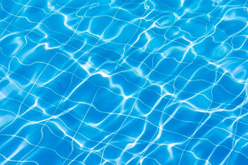 Top-down view of clear blue swimming pool water with sunlight reflections over a blue tiled liner pattern | HB Pools
