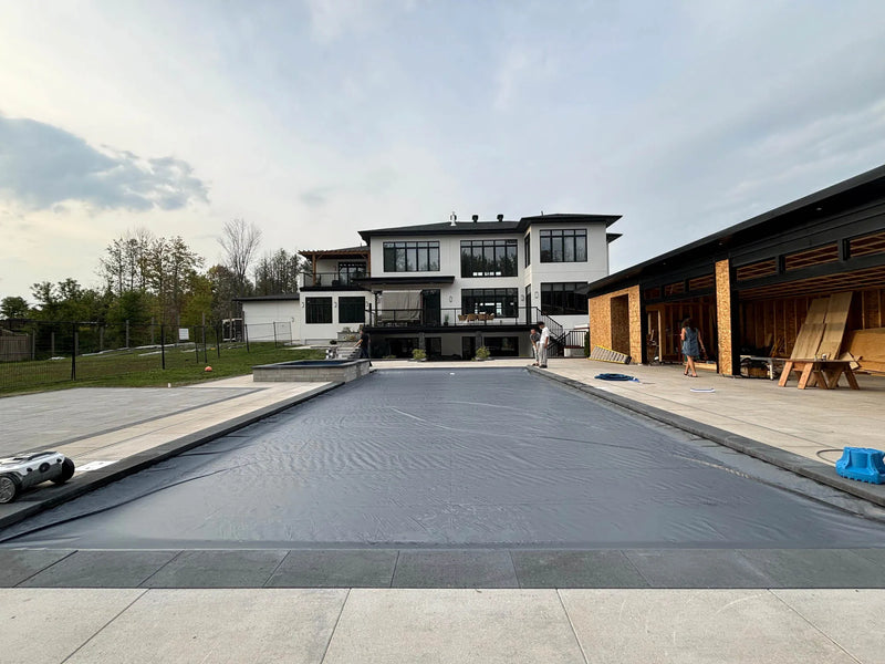 Large rectangular pool with a grey safety cover installed, showcasing a professional pool closing or renovation site | HB Pools