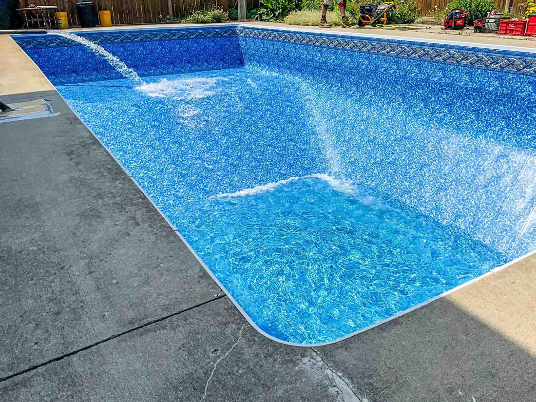 A new blue-patterned pool liner is being installed and filled with water from a hose in a backyard inground pool. | HB Pools