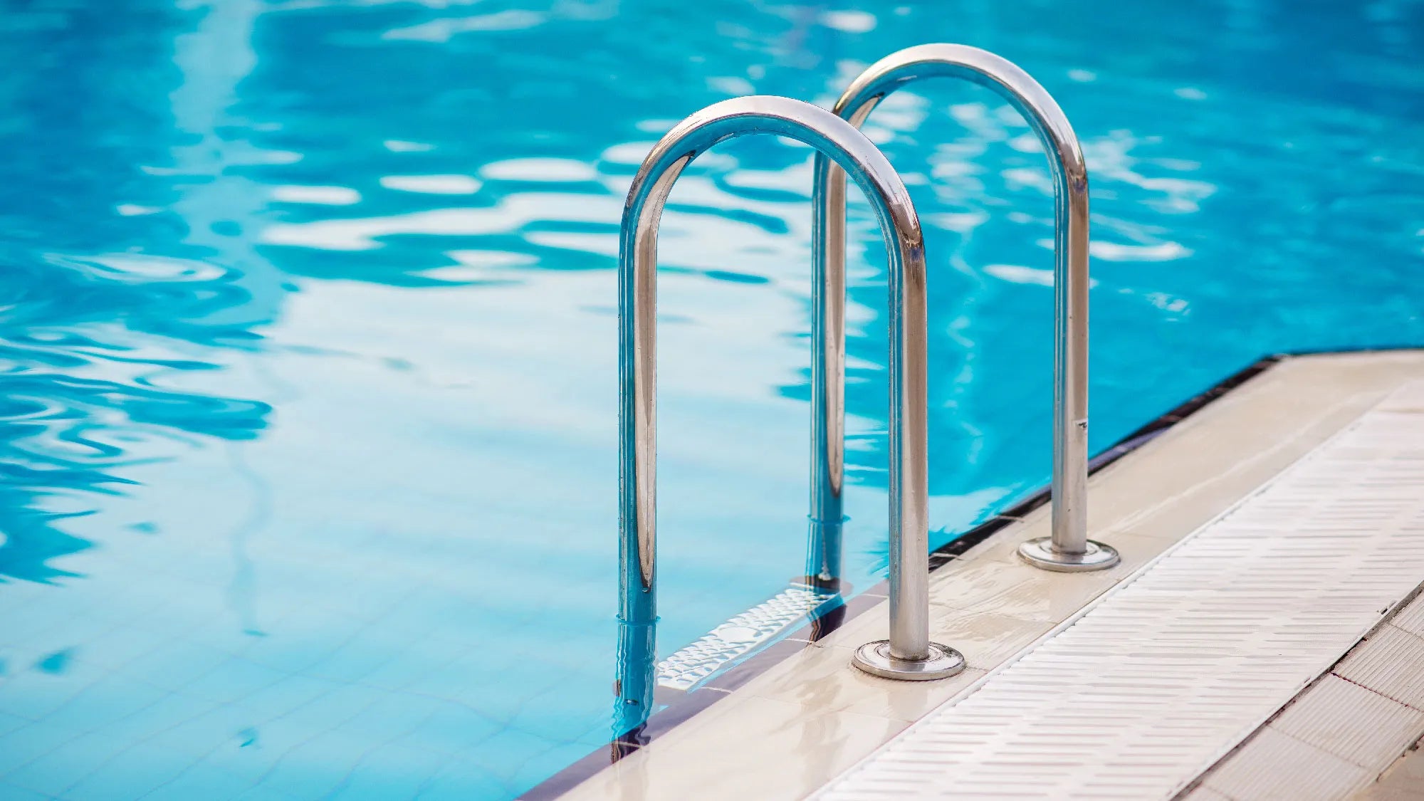 Clean blue swimming pool with polished chrome ladder after professional pool opening services | HB Pools