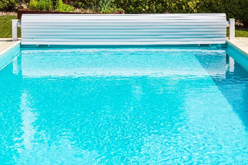 Clean backyard swimming pool with a white automatic pool cover | HB Pools