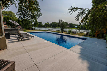 Swimming pool with lounge chairs and trees in the background | HB Pools