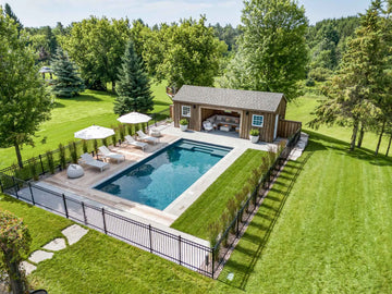 Backyard with pool, cabana, and outdoor furniture surrounded by trees | HB Pools