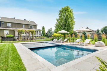 Backyard with pool, lounge chairs, and a house in the background | HB Pools